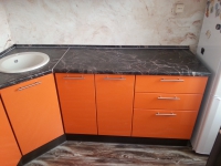 Оранжевая угловая кухня с накладной мойкой белого цвета
