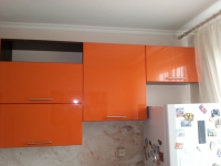 Оранжевая угловая кухня с накладной мойкой белого цвета